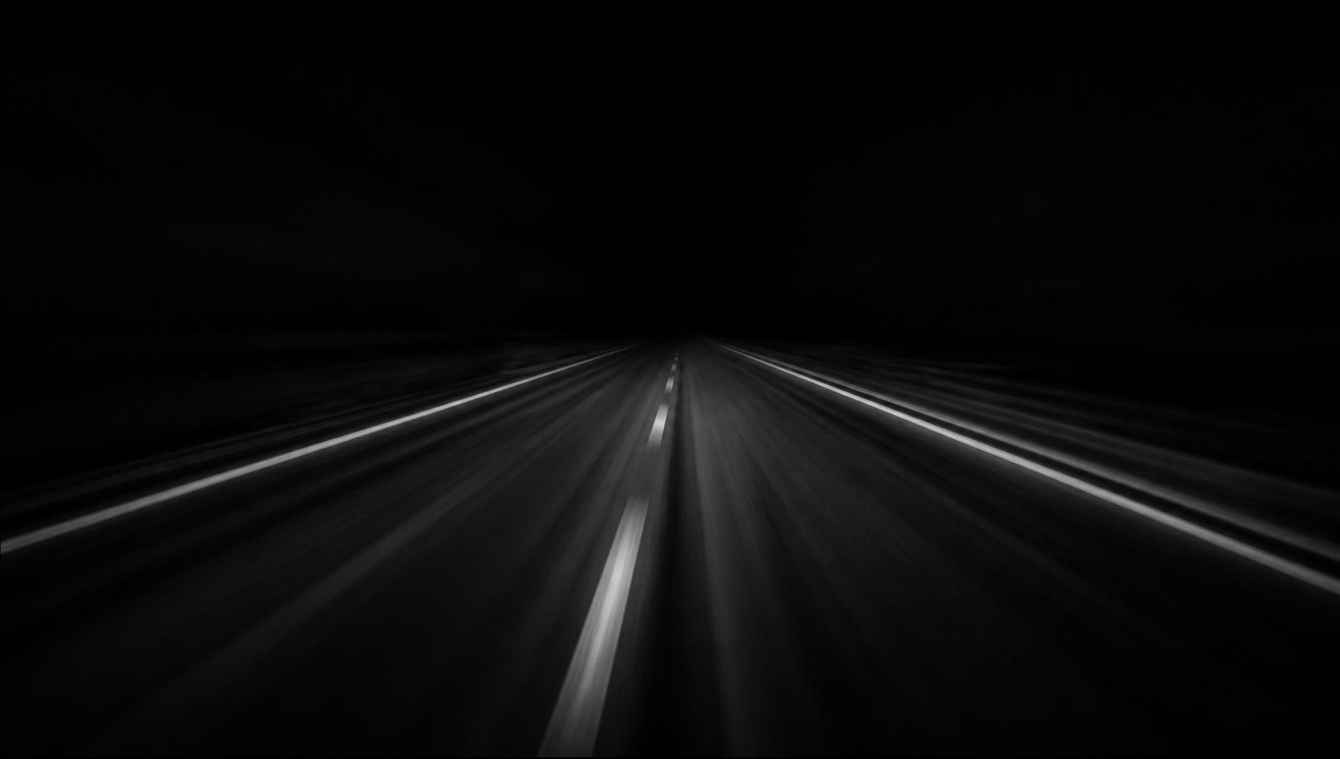Dark highway lane markings streaking into the night